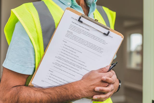 person in safety vest holding a home inspection checklist